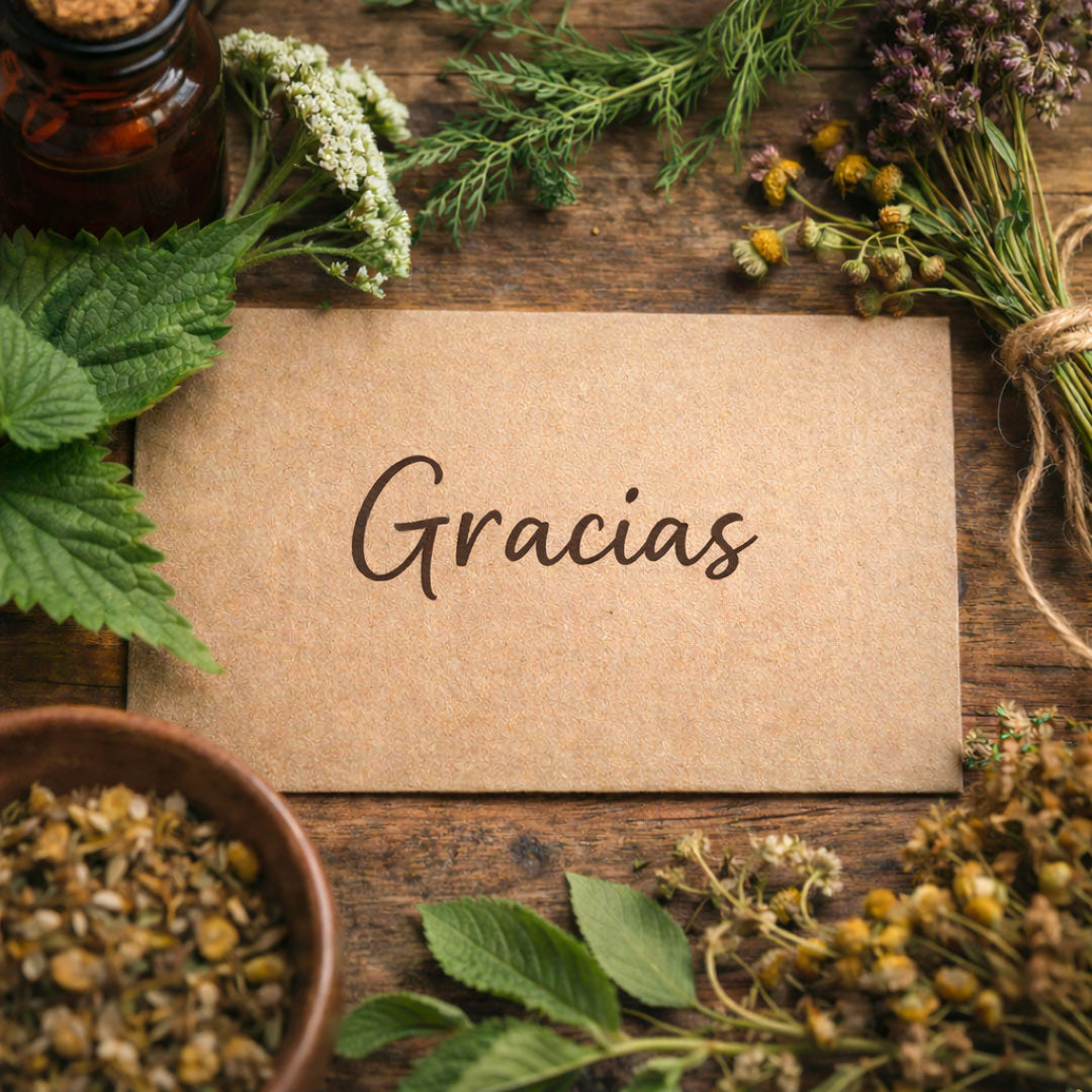 Kraft paper card with 'Gracias' surrounded by herbs and plants on a wooden surface